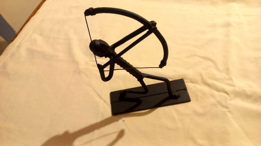 Escultura metálica de arquero en acción — figura artística en metal negro mate con base sólida, obra de HeraldWeid